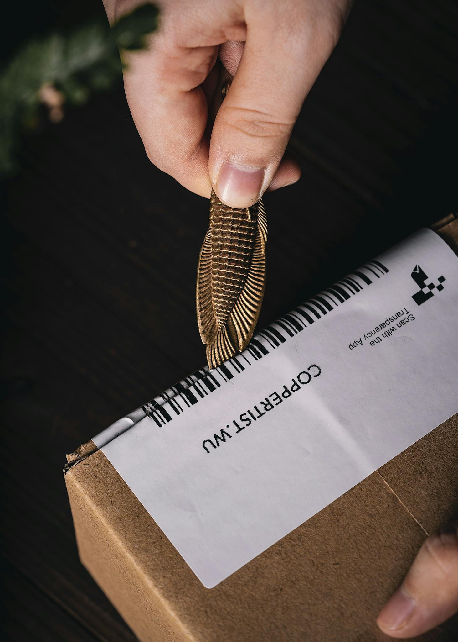 Close-up of a hand opening a package with a wooden tool, ideal for delivery or ecommerce themes.